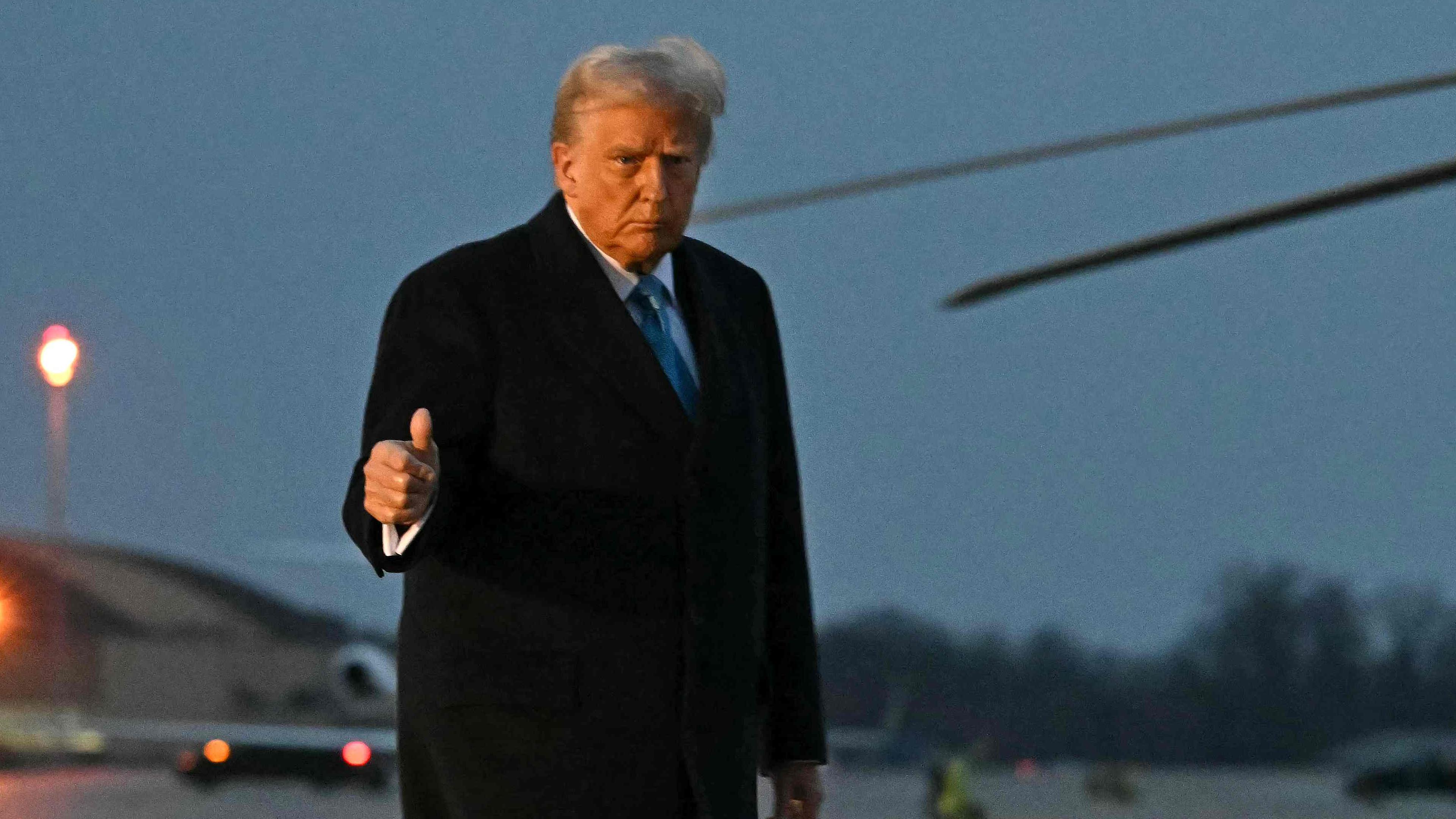 Donald Trump auf einem Flugplatz, zeigt einen Daumen hoch.