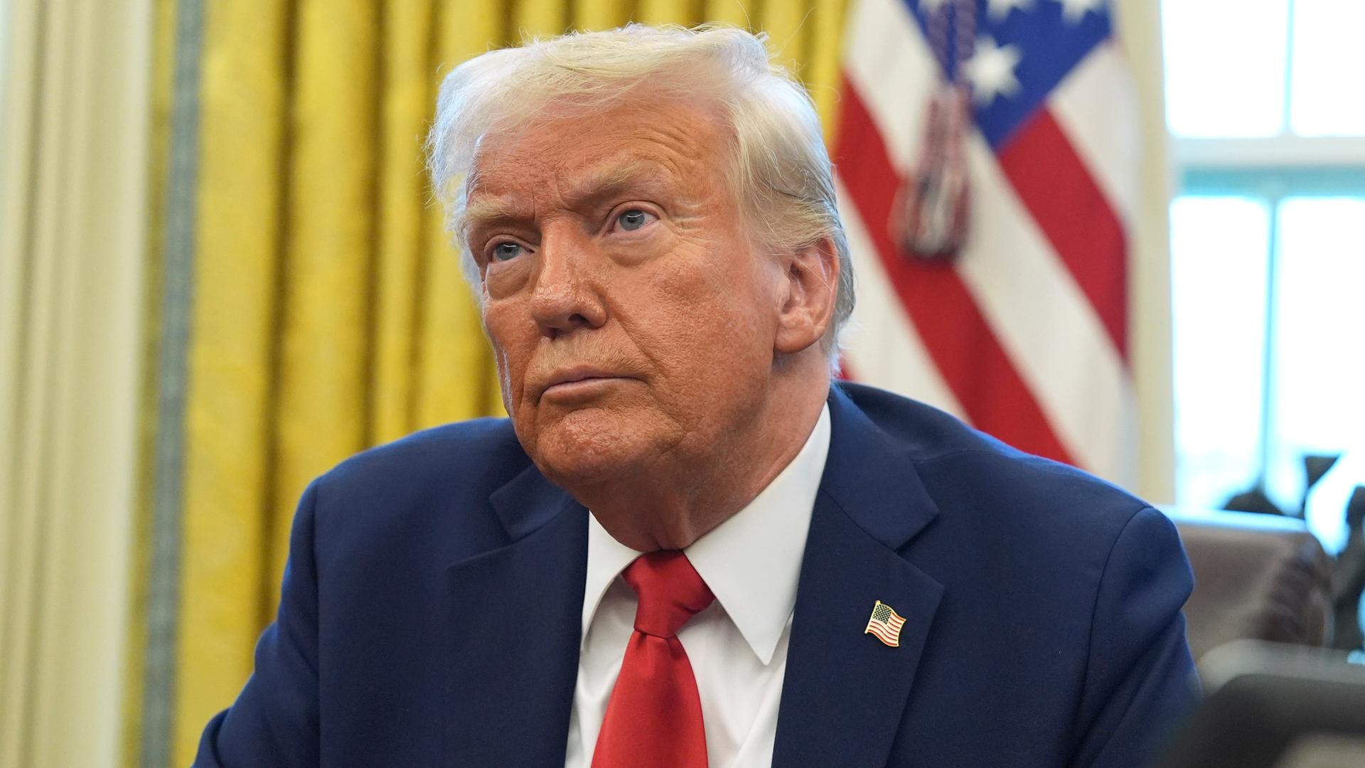 Donald Trump sitzt am Schreibtisch im Oval Office des Weißen Hauses. 