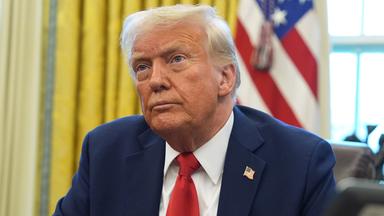 Donald Trump sitzt am Schreibtisch im Oval Office des Weißen Hauses. 