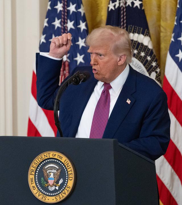 US-Präsident Donald Trump vor US-Flaggen mit erhobenem Arm.