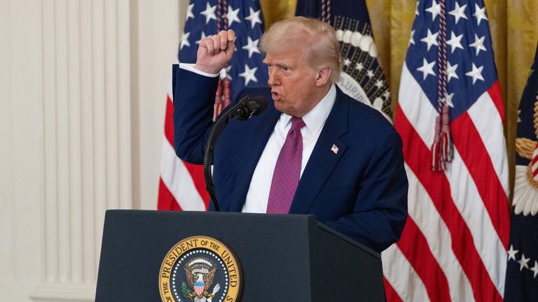 US-Präsident Donald Trump vor US-Flaggen mit erhobenem Arm.