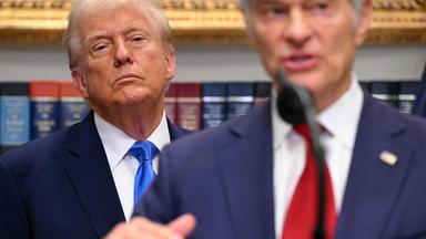 Donald Trump schaut kritisch aus dem Hintergrund zu Mehmet Oz