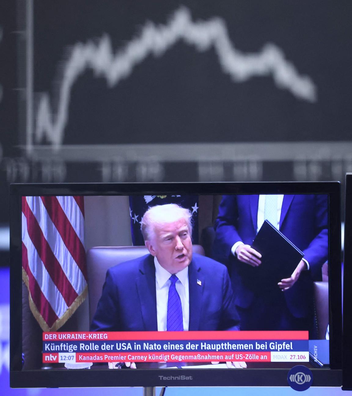 US-Präsident Donald Trump ist auf einem Fernsehbildschirm unter einer Anzeige des Deutschen Aktienindex DAX an der Frankfurter Börse zu sehen.