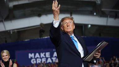 Donald Trump reckt auf einer Bühne einen Arm in die Höhe.
