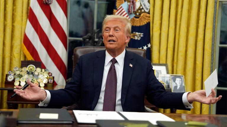 Donald Trump sitzt im Oval Office und hält einen Brief in der Hand.