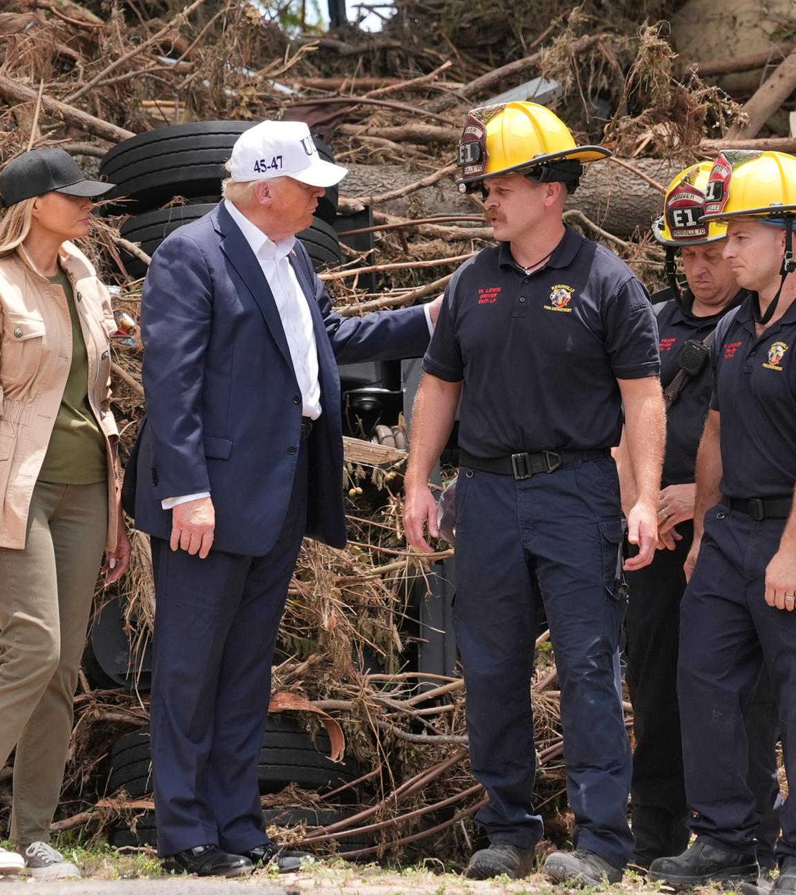 Donald und Melania Trump im Gespräch mit Ersthelfern bei der Flut, im Hintergrund ein Haufen aus Reifen und Ästen