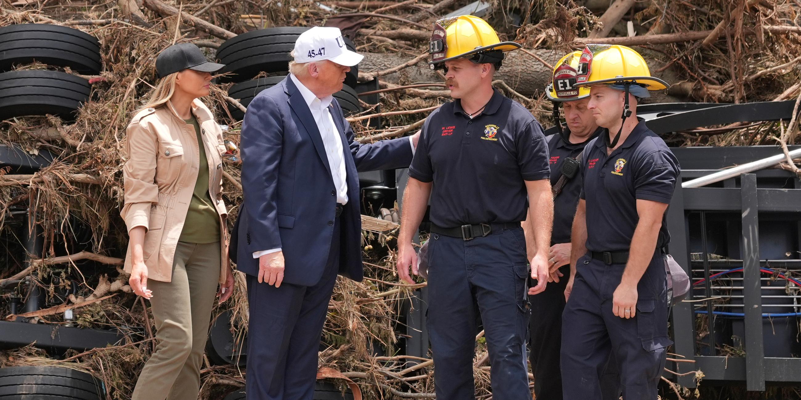 Donald und Melania Trump im Gespräch mit Ersthelfern bei der Flut, im Hintergrund ein Haufen aus Reifen und Ästen