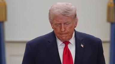 Donald Trump schaut nach unten zum Boden.