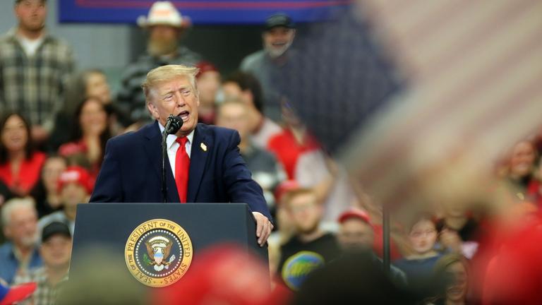 Donald Trump steht auf einer Bühne in einer Menschenmenge.