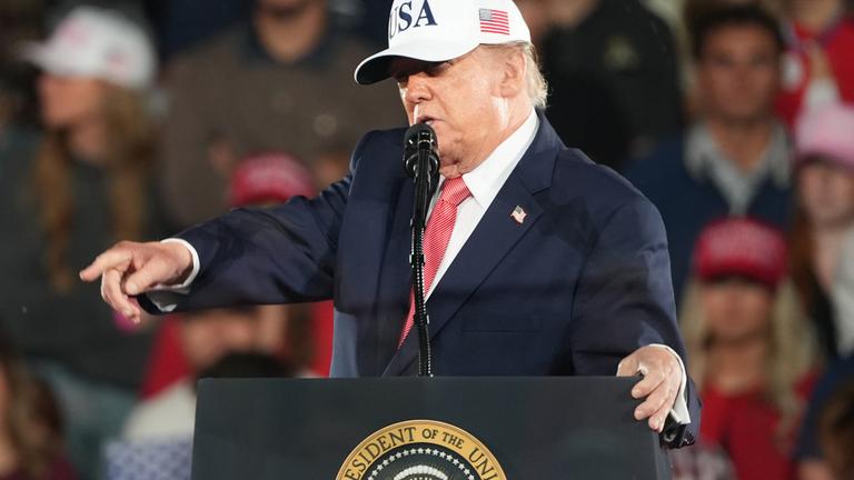 Donald Trump steht hinter einem Rednerpult auf einer Wahlkampfveranstaltung in North Carolina und zeigt in die Menge.
