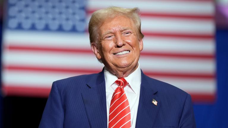 "Donald Trump: Rückkehr an die Macht": Vor der amerikanischen Flagge lächelt Trump in die Kamera