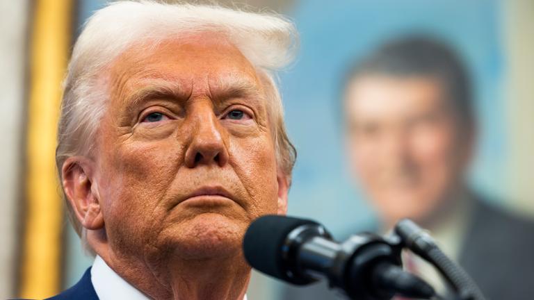 Donald Trump steht an einem Mikrofon im Weißen Haus.