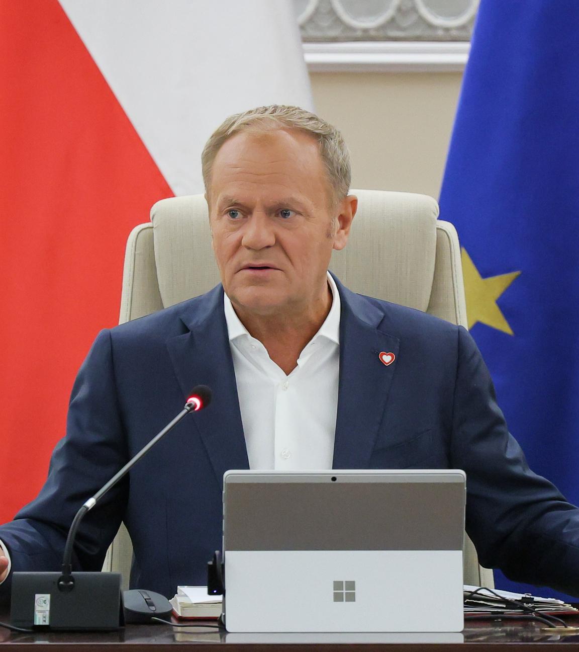 Donald Tusk sitzend vor einer polnischen und einer EU-Fahne