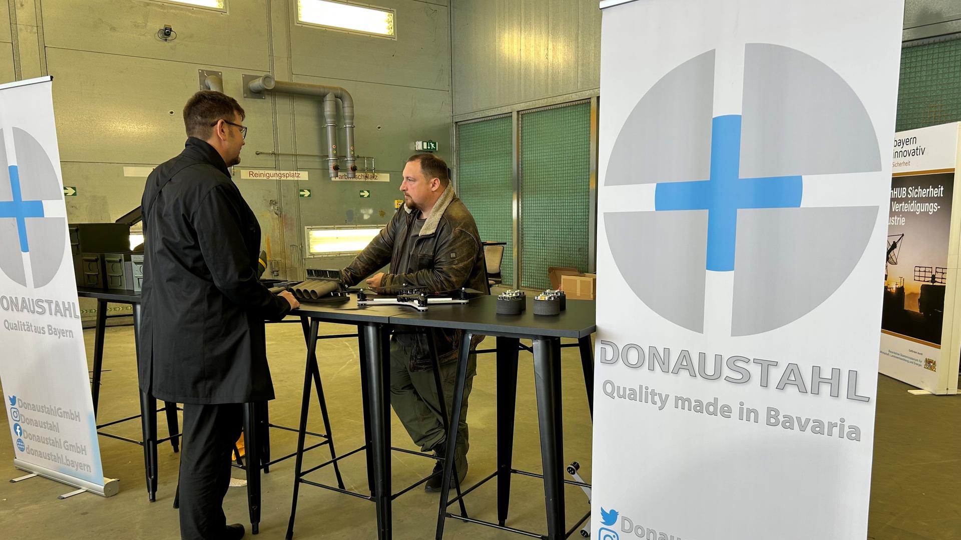 Zwei Personen unterhalten sich am Stand von "Donaustahl" auf dem Defence TechDay.
