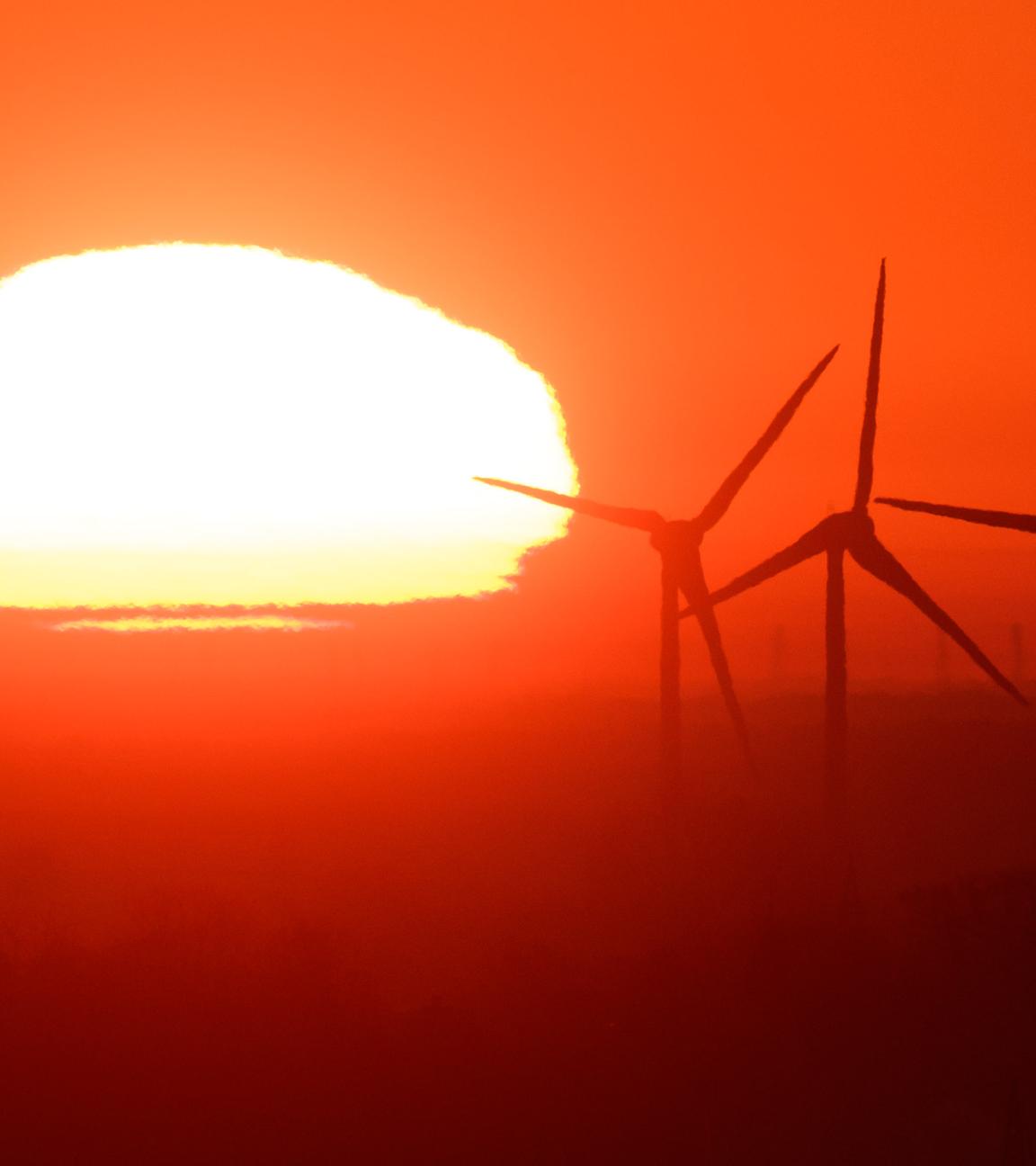  Die Sonne geht hinter Windräder in der Region Hannover auf. 
