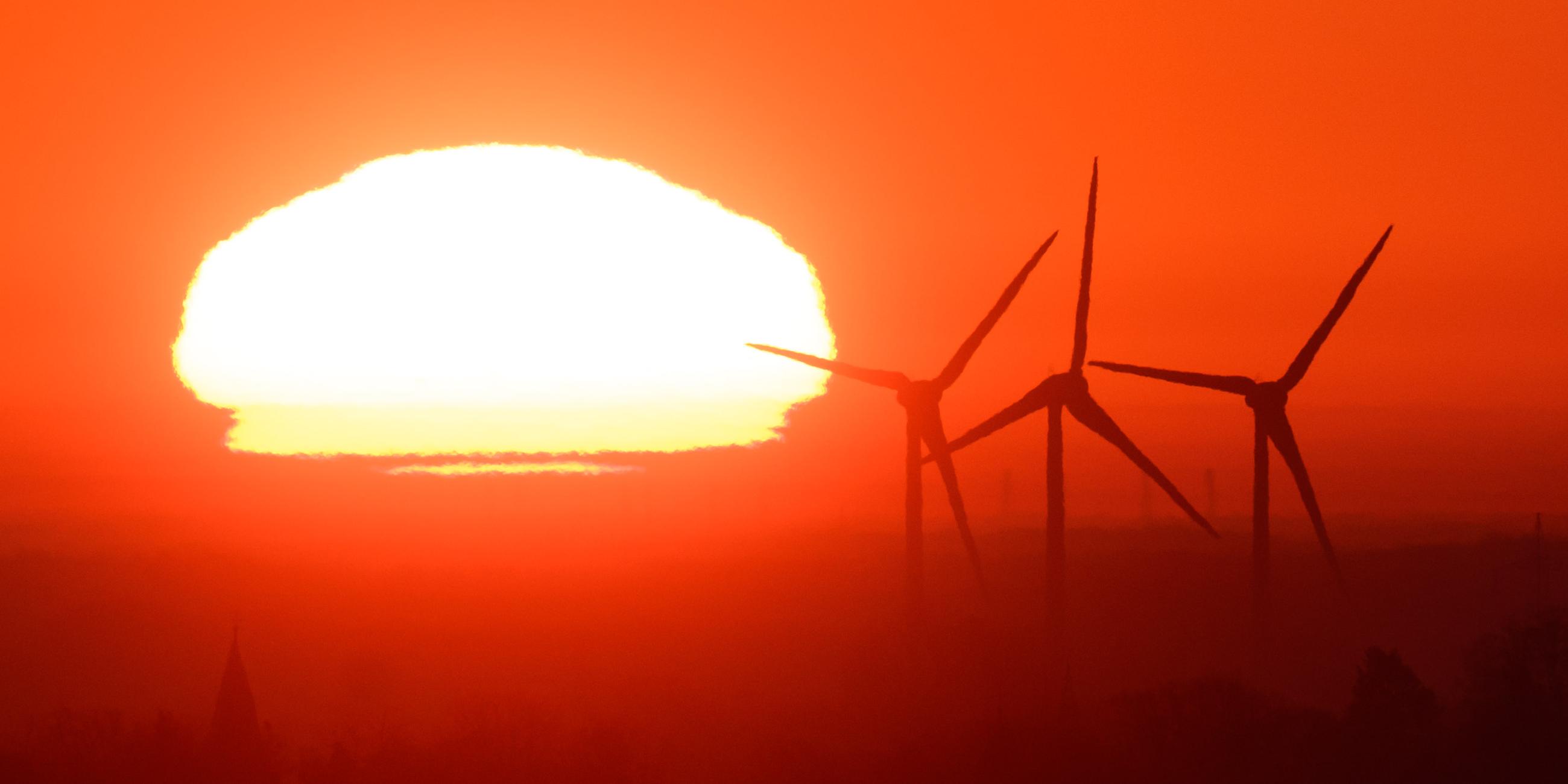  Die Sonne geht hinter Windräder in der Region Hannover auf. 