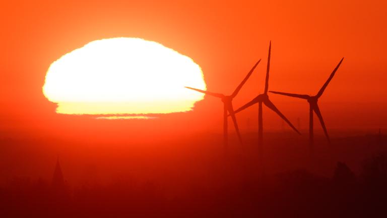  Die Sonne geht hinter Windräder in der Region Hannover auf. 