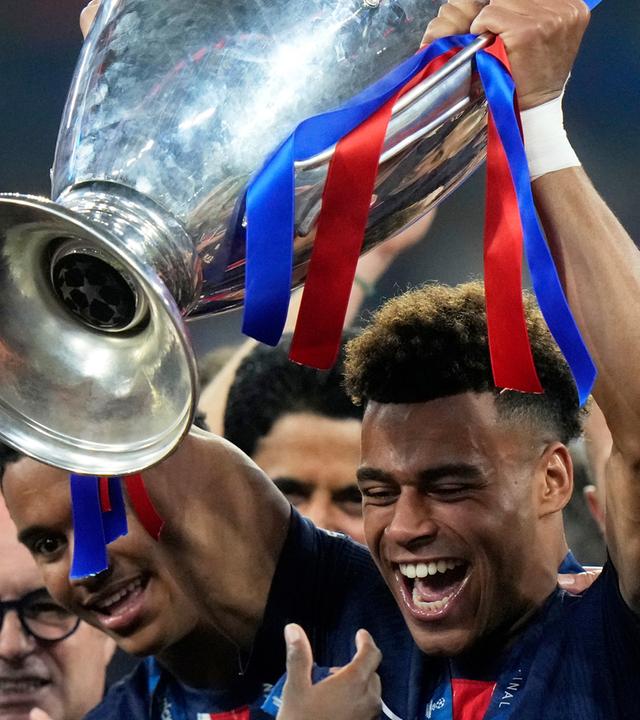 Desire Doue hält den Pokal des Champions League Finales in der Allianz Arena in München am 31.05.2025.