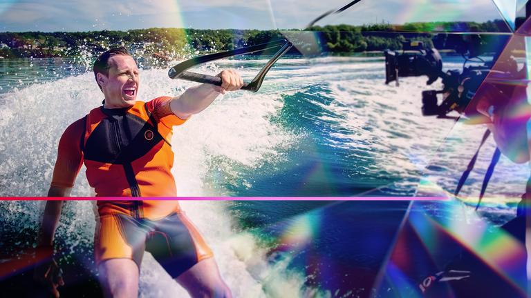 Schauspieler Patrick Kalupa fährt bei Dreharbeiten Wasserski und hält sich mit nur einer Hand fest.