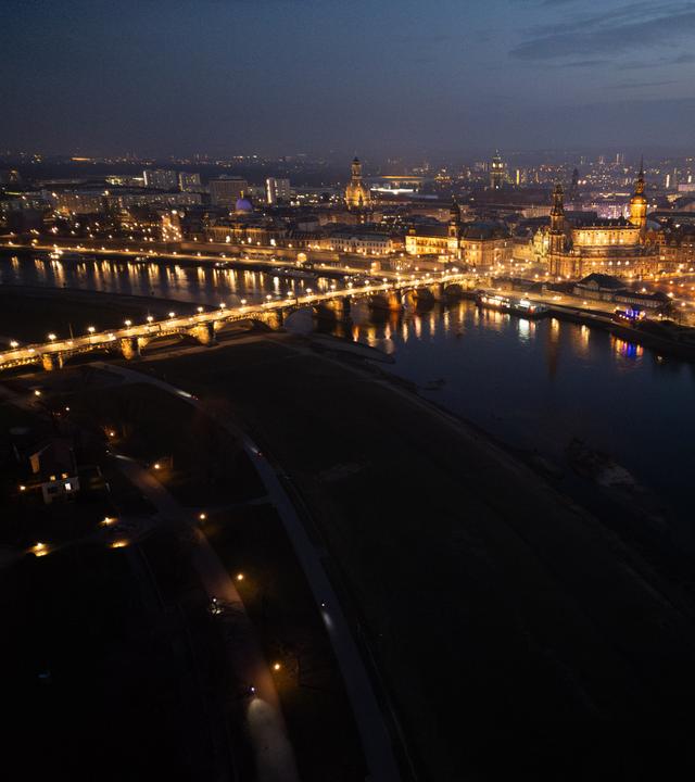 Blick am Abend auf die historische Altstadtkulisse an der Elbe mit der der Kuppel der Kunstakadmie mit dem Engel ·Fama· (l-), der Frauenkirche, dem Ständehaus, der Hofkirche, dem Rathaus, dem Hausmannsturm, der Kreuzkirche und der Semperoper. Am 13. Februar 2025 jährt sich die Zerstörung Dresdens durch anglo-amerikanische Bomben zum 80. Mal. (Luftaufnahme mit Drohne)
