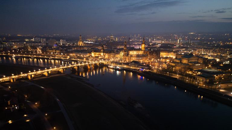 Blick am Abend auf die historische Altstadtkulisse an der Elbe mit der der Kuppel der Kunstakadmie mit dem Engel ·Fama· (l-), der Frauenkirche, dem Ständehaus, der Hofkirche, dem Rathaus, dem Hausmannsturm, der Kreuzkirche und der Semperoper. Am 13. Februar 2025 jährt sich die Zerstörung Dresdens durch anglo-amerikanische Bomben zum 80. Mal. (Luftaufnahme mit Drohne)