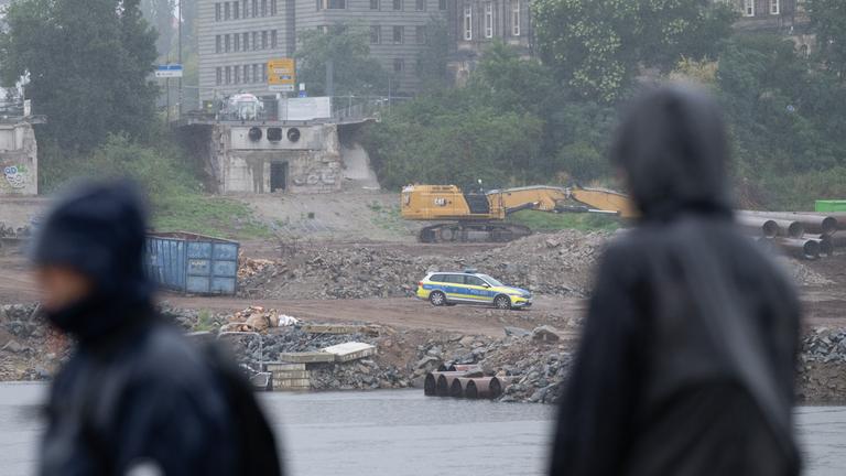 Ein Polizeifahrzeug steht auf der Baustelle an der abgerissenen Carolabrücke auf der Neustädter Elbseite.