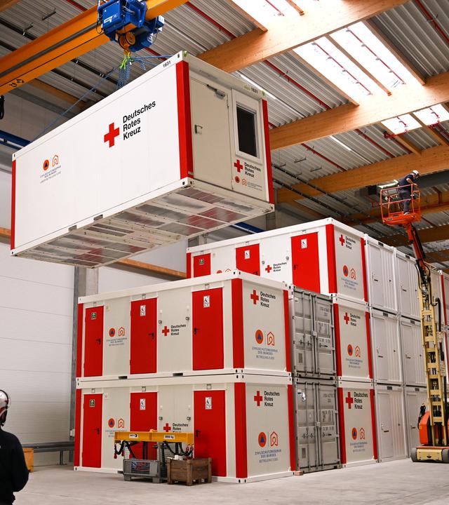 Ein Hallenkran hebt einen Container des Deutschen Roten Kreuzes (DRK) in einer Lagerhalle des neuen bundesweiten Bevölkerungsschutzzentrums in Luckenwalde an.
