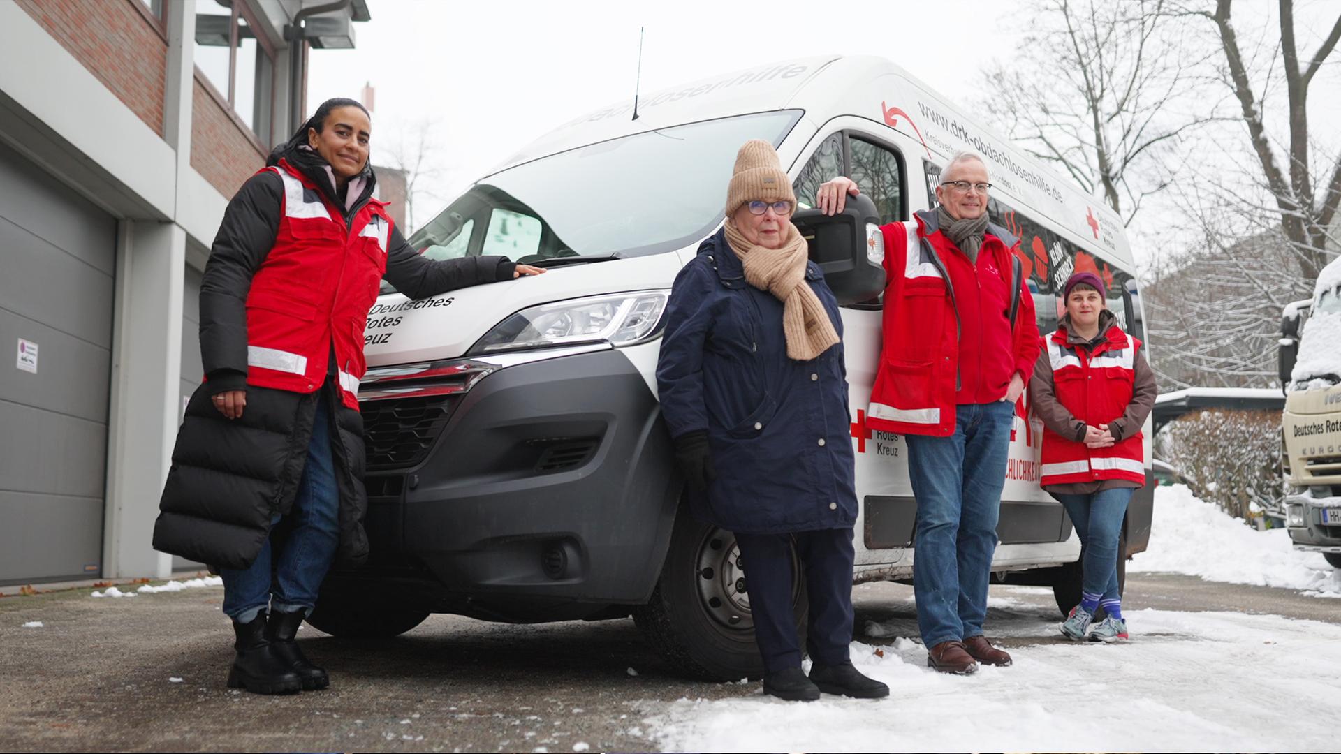 Die Gruppe der DRK Obdachlosenhilfe Hamburg posiert vor ihrem Auto.