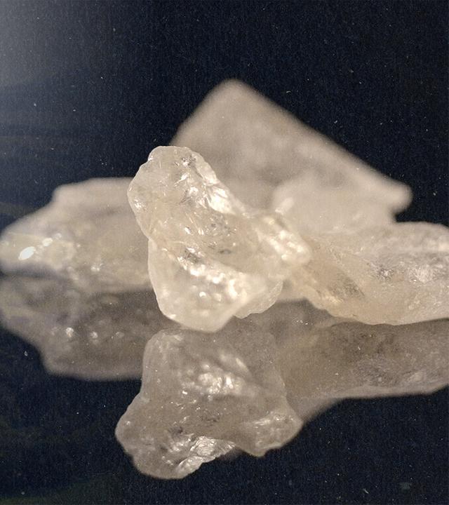 Montage: Auf der einen Seite liegt ein Dorf umgeben von Wiesen und Bäumen, auf der anderen Seite Crystal Meth in der Nahaufnahme.