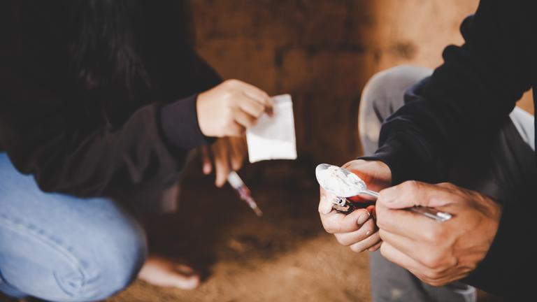 Die Hände von zwei jungen Personen, die Drogen nehmen, werden gezeigt.