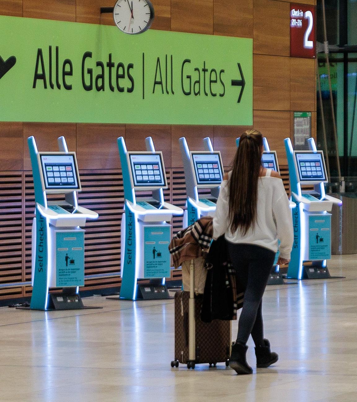 Eine Frau geht mit einem Koffer durch einen menschenleeren Flughafen. 