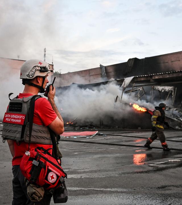 Ukrainischer Sanitäter steht vor einem Brand.