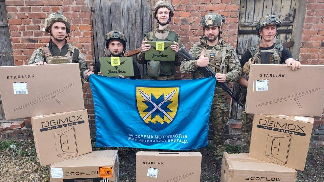 Fünf ukrainische Soldaten der Brigade Mariupol stehen vor Kartons mit Drohnenausrüstung.