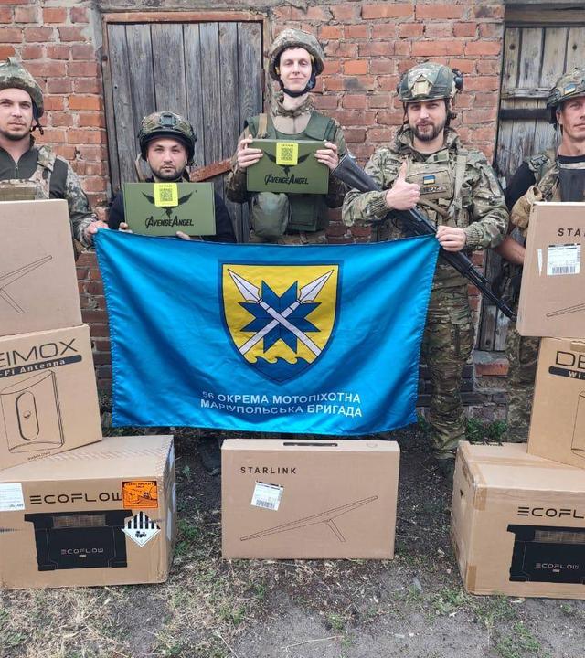 Fünf ukrainische Soldaten der Brigade Mariupol stehen vor Kartons mit Drohnenausrüstung.