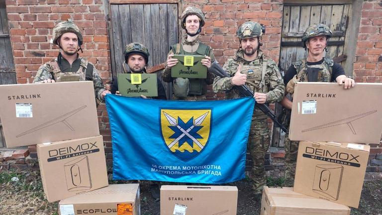 Fünf ukrainische Soldaten der Brigade Mariupol stehen vor Kartons mit Drohnenausrüstung.