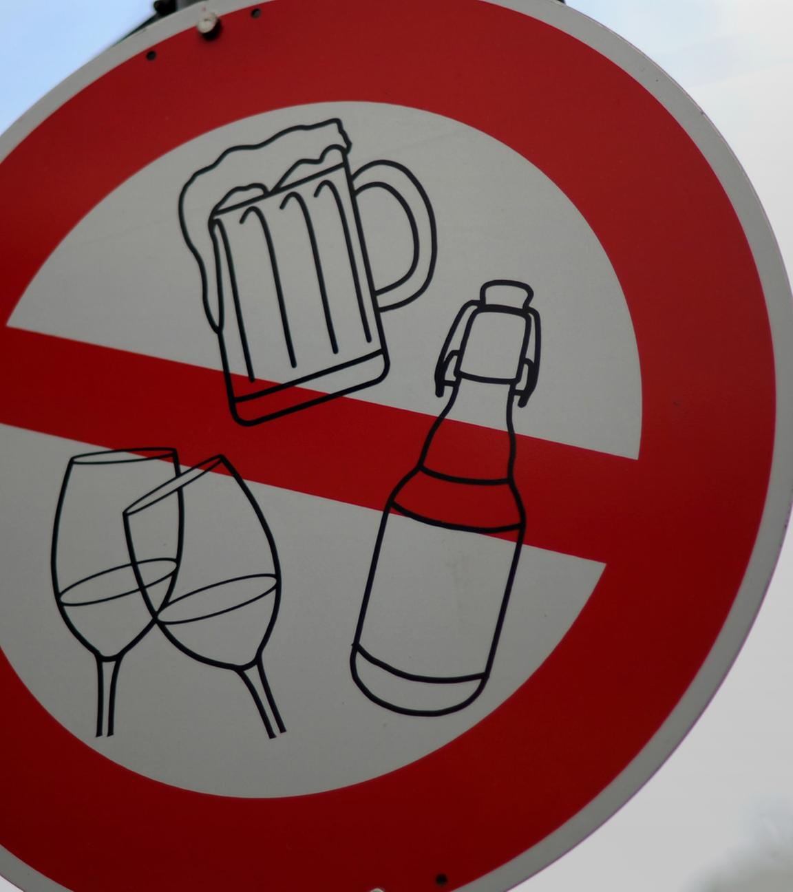 Auf einem Verkehrsschild sind Symbole für alkoholische Getränke wie Bier und Wein durchgestrichen.