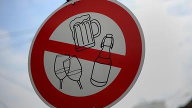 Auf einem Verkehrsschild sind Symbole für alkoholische Getränke wie Bier und Wein durchgestrichen.