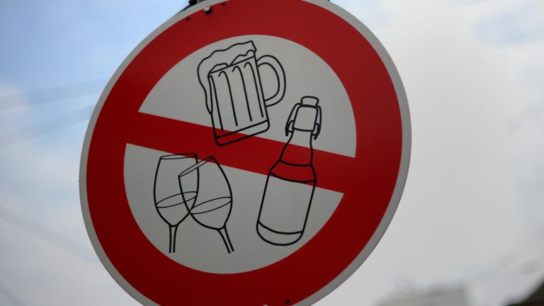 Auf einem Verkehrsschild sind Symbole für alkoholische Getränke wie Bier und Wein durchgestrichen.