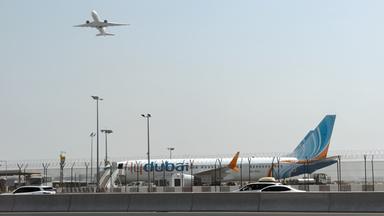 Ein Flugzeug hebt ab, während ein Flugzeug der Fluggesellschaft Flydubai auf dem Rollfeld des Dubai International Airport steht.