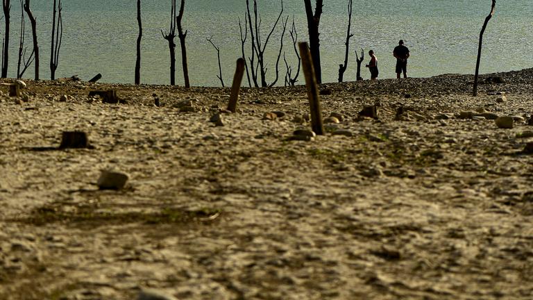 Menschen spazieren an einem sonnigen Sommertag am Ufer des von der Dürre betroffenen Yesa-Stausees in Nordspanien entlang.