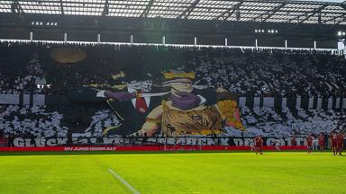 Auf einem riesigen Bild, das einen großen Teil der Südtribüne des RheinEnergie-Stadions geziert hatte, war ein Mann mit FC-Krawatte zu sehen, der ein Messer an die Kehle von Glücksgöttin Fortuna hielt.
