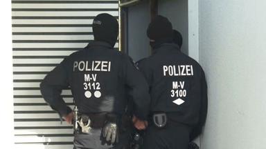 Zwei maskierte Polizisten von hinten.