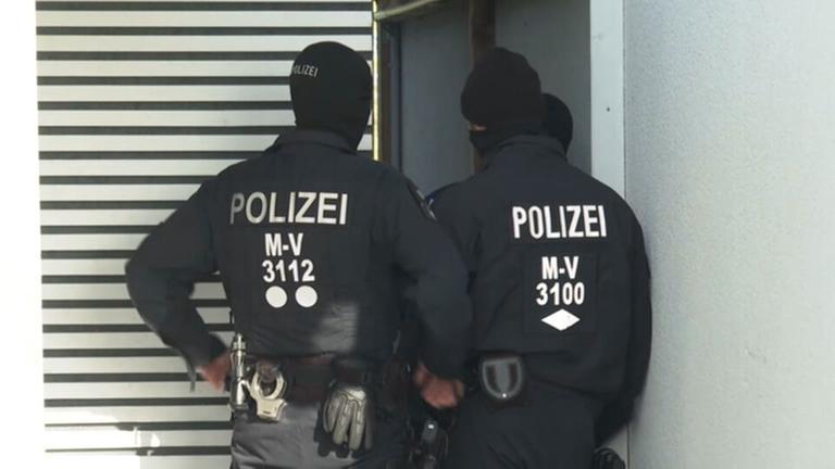 Zwei maskierte Polizisten von hinten.