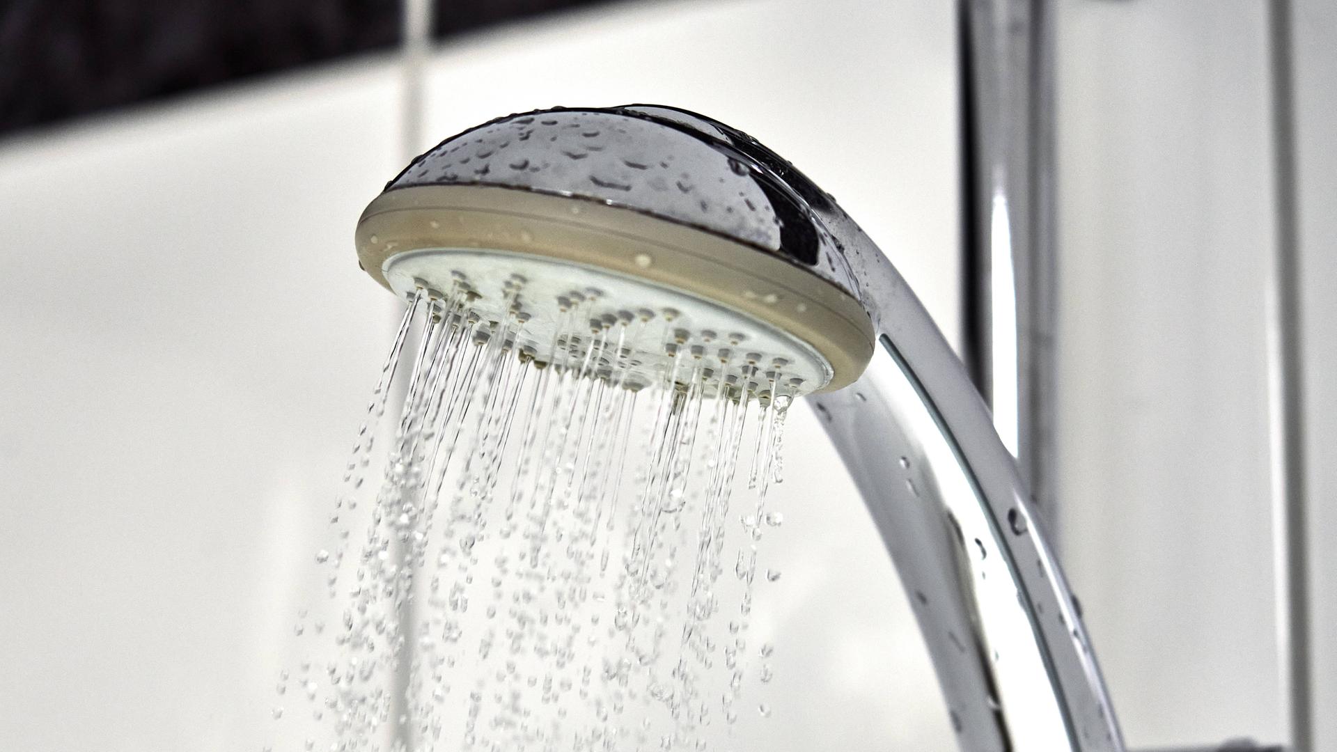 Wasser fließt aus einem Duschkopf in einer Dusche im Badezimme