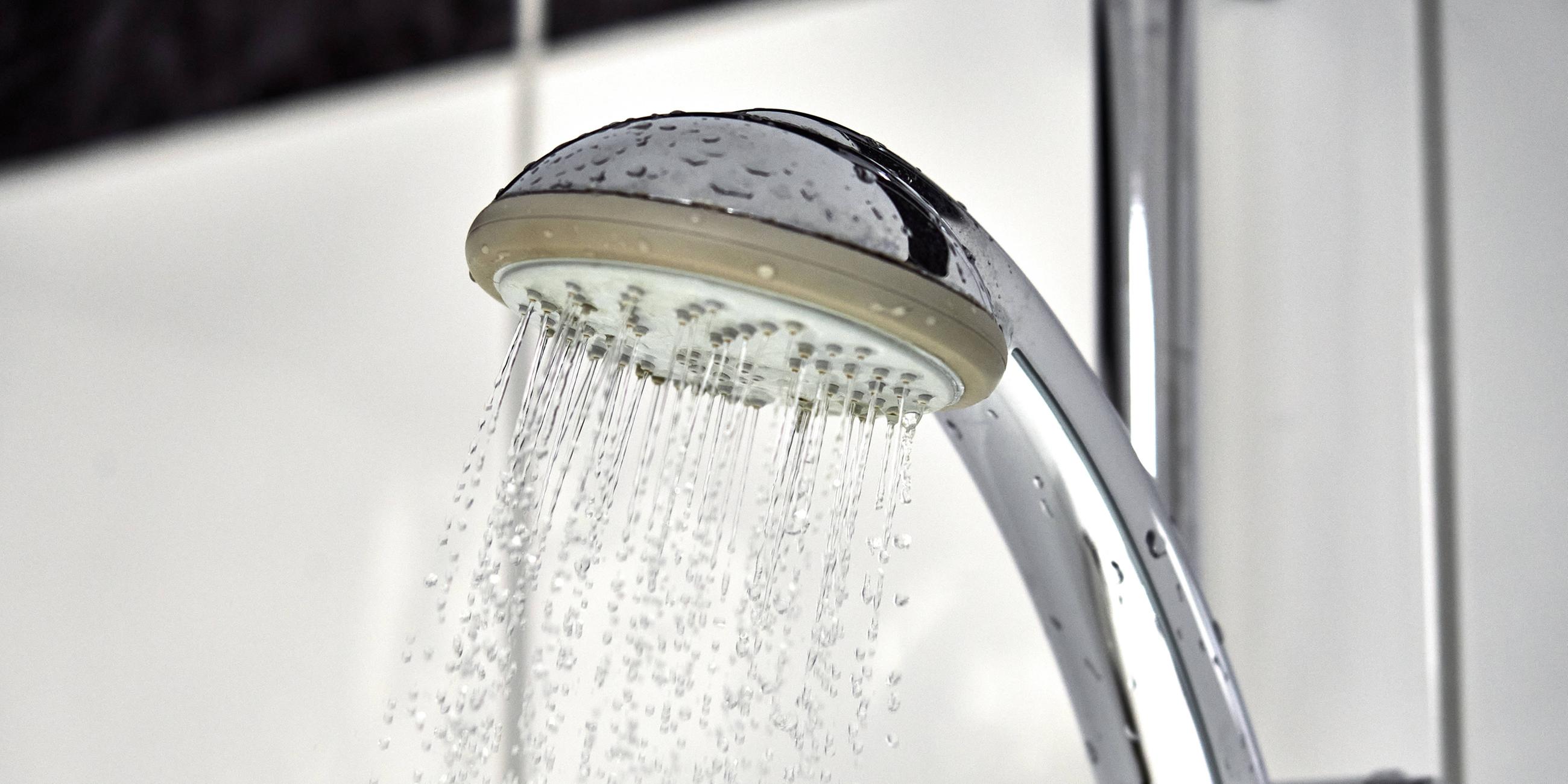 Wasser fließt aus einem Duschkopf in einer Dusche im Badezimme