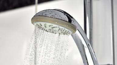 Wasser fließt aus einem Duschkopf in einer Dusche im Badezimme