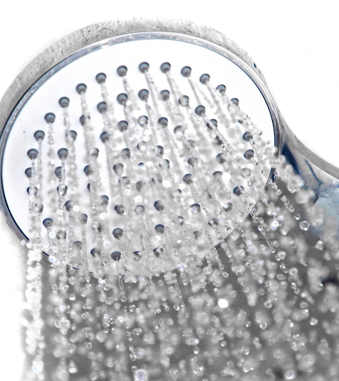 Aus einem Duschkopf läuft Wasser (Nahaufnahme).