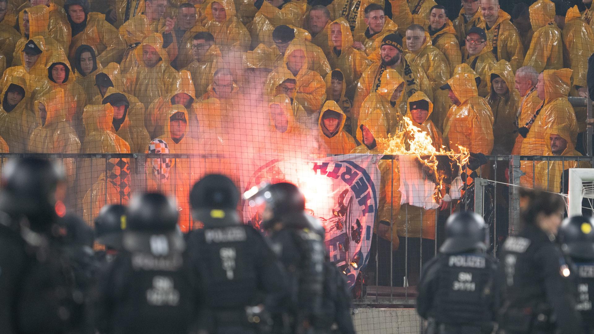 Polizisten stehen während einer Spielunterbrechung im Stadion vor dem K-Block mit Dresdner Fans am 04.04.2026 in Dresden.