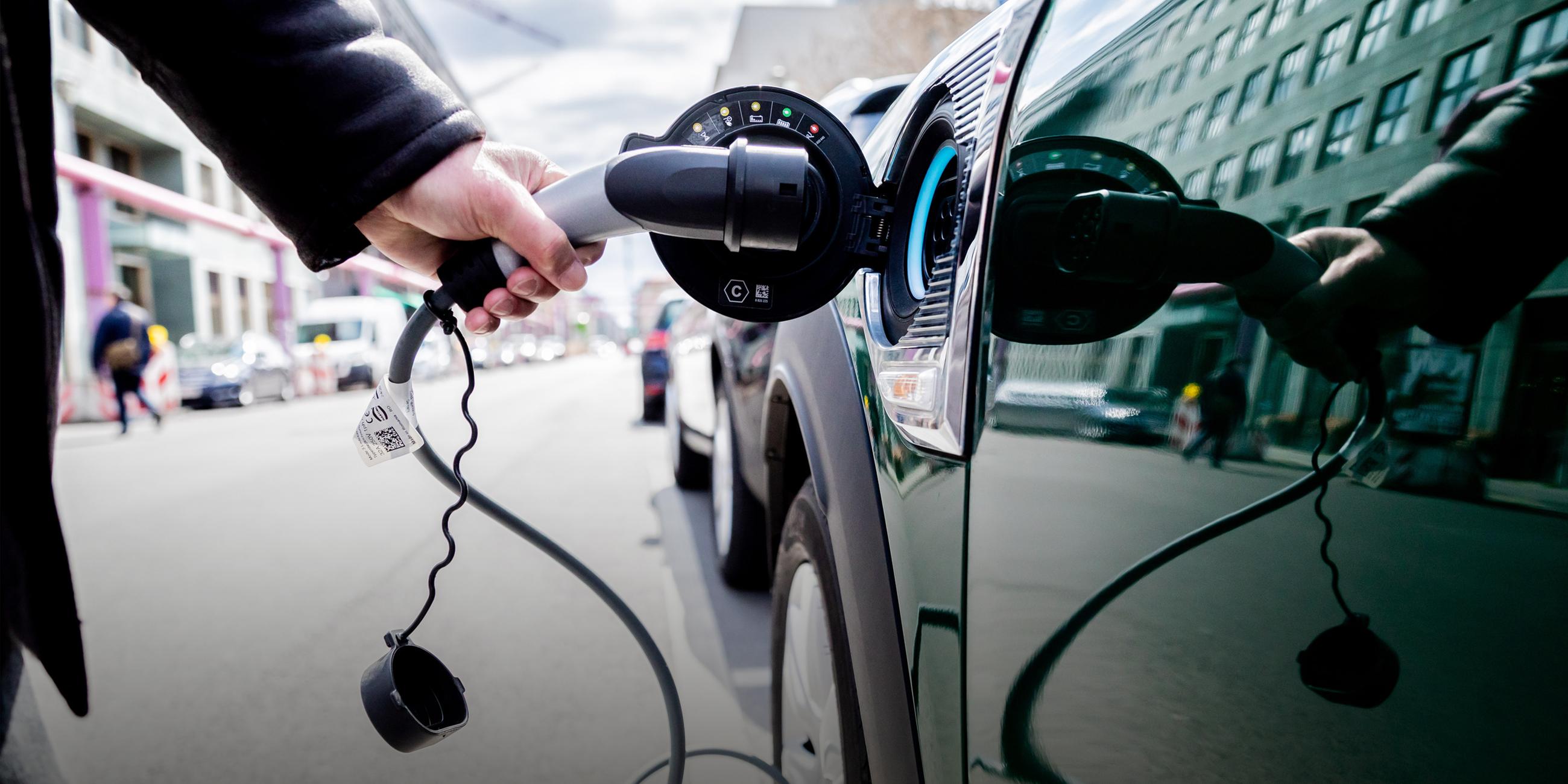 Ein Mann nimmt an einem Auto mit Plug-in-Hybrid-Antrieb in Berlin-Mitte den Ladestecker raus. 