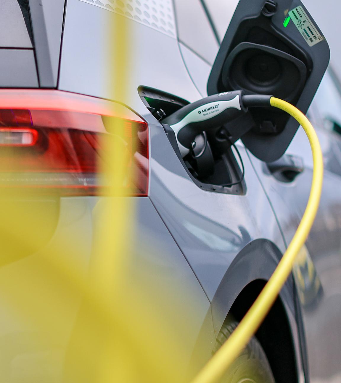 Ein Elektrofahrzeug von Volkswagen lädt mit einem gelben Kabel an einer Ladesäule. (Archiv)